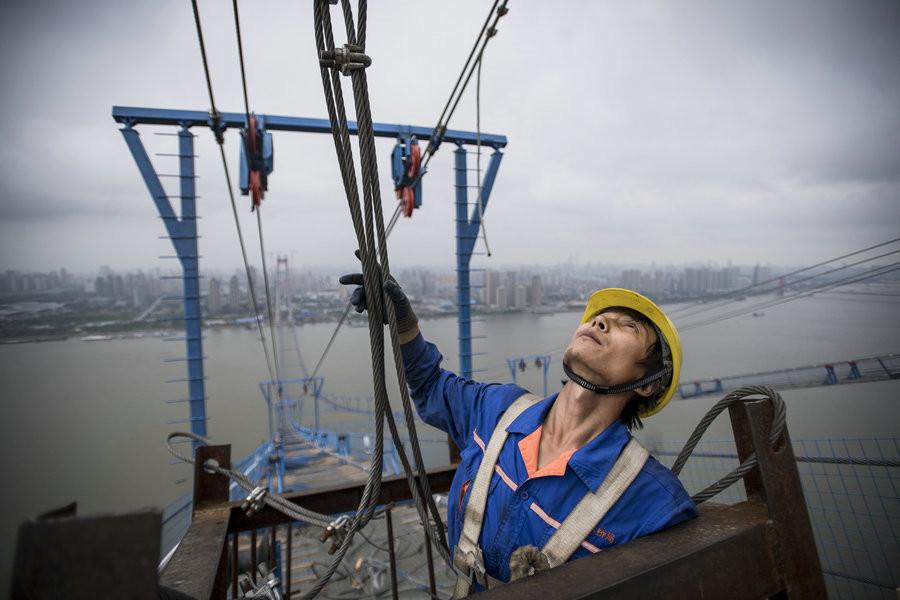 Chen Xiaohui, 34, from Wuhan, is responsible for receiving construction materials from the tower crane.[Photo/Xinhua]