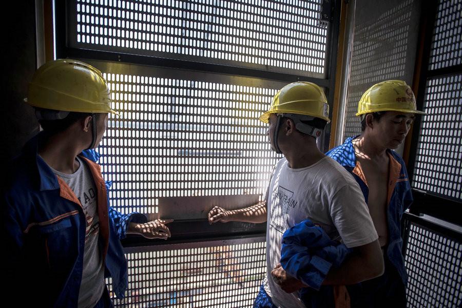 Huang Hua (middle), 41, and his fellow workers take an elevator to work. It takes more than seven minutes to get to the top.[Photo/Xinhua]

At present, due to high temperature, workers start at 5 or 6 o\'clock every morning. Then they take a break at noon, the hottest time of the day, and return to the ground in the evening.