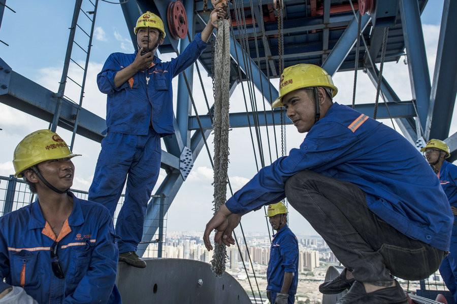 Liu Neng (second from left) and fellow workers take a break.[Photo/Xinhua]