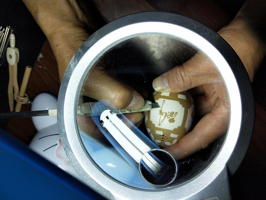 Tai Xinchu works on an egg carving. (Photo by Yao Daojun/for chinadaily.com.cn)