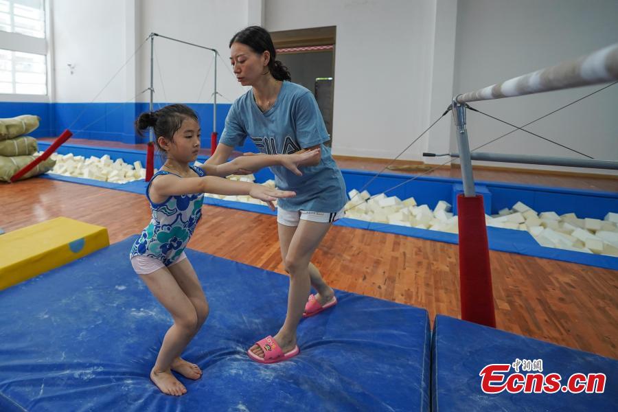 <?php echo strip_tags(addslashes(Instructor Wei Hong trains a student at the Amateur Children's Gymnastics Training School in Rongjiang County, Southwest China’s Guizhou Province, July 16, 2018. There are 60 children taking part in gymnastics training at the school during their spare time. Since 1972, the county has sent 21 athletes to the provincial gymnastics and gymnastics trampoline teams, among whom six later became national team members. The county is home to Liu Rongbing, who won a gold medal for the men's team in the 2014 World Artistic Gymnastics Championships. (Photo: China News Service/He Junyi))) ?>