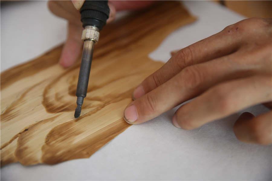 Ding Xisen irons a straw painting on July 15, 2018. (Photo/Asianewsphoto)