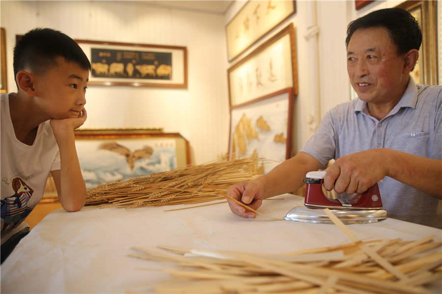 Xu Hao, a primary school student, watches Ding iron wheat straws. (Photo/Asianewsphoto)