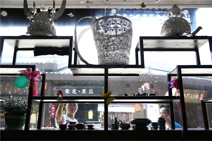 Wang examines the window display of his shop at Danzhai county, Southwest China\'s Guizhou Province, July 12, 2018. (Photo//Asianewsphoto)
