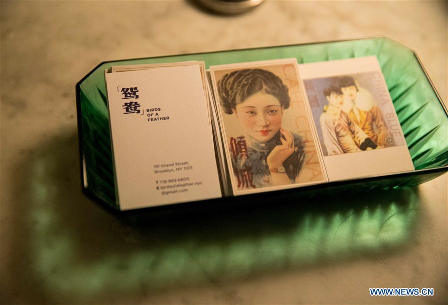 Photo taken on June 27, 2018 shows the business cards of three restaurants opened by Wang Yiming and Zhang Xian, at Cafe China in New York, the United States. Walking in the bustling street of midtown Manhattan, you may not notice Cafe China if there weren\'t so many people waiting for seats outside the Chinese restaurant. Although the space is limited and decoration not so luxury, Cafe China has won Michelin one star for six consecutive years from 2012 to 2017. Wang Yiming and Zhang Xian, a couple from China, quit their well-paid financial jobs in New York and opened Cafe China with the ambition to provide authentic Sichuan cuisine along with a comfortable dining environment. They decided not to sell American-Chinese dishes like most Chinese restaurants did at that time. Meanwhile, the couple decorated the place with items such as vintage posters, antique cameras and lamps to create an old Shanghai style. At the beginning, their idea was strongly opposed by many friends and even their staff, as the American-Chinese food was the easiest way to make money at that time. However, it surprised them that many Americans swarmed to Cafe China with curiosity for decent Chinese dishes and the unique dining environment as soon as the restaurant just opened. The couple believed the success of Cafe China resulted from not only the appeal of authentic Chinese food but also the sophisticated Chinese culture behind it. \