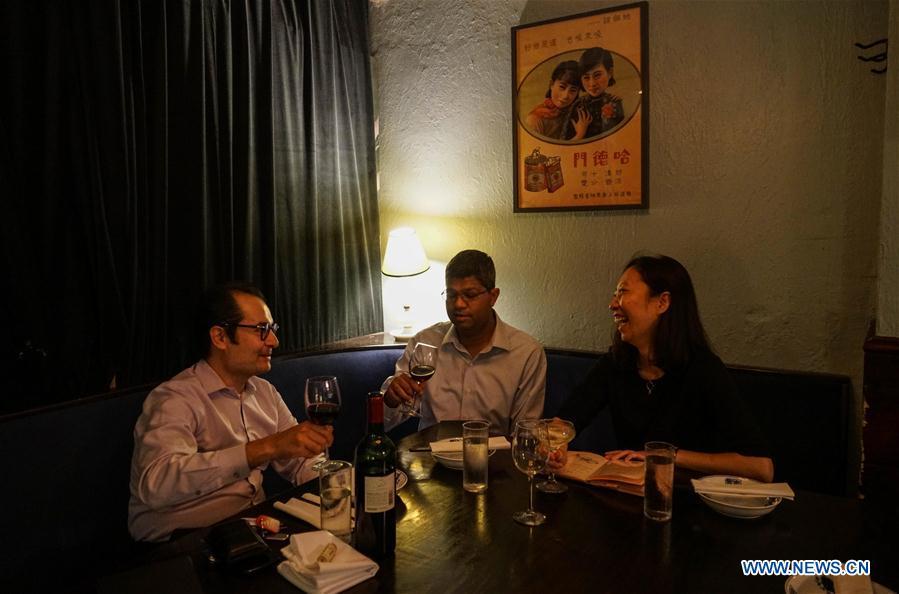 Customers have dinner at Cafe China in New York, the United States, on June 27, 2018. Walking in the bustling street of midtown Manhattan, you may not notice Cafe China if there weren\'t so many people waiting for seats outside the Chinese restaurant. Although the space is limited and decoration not so luxury, Cafe China has won Michelin one star for six consecutive years from 2012 to 2017. Wang Yiming and Zhang Xian, a couple from China, quit their well-paid financial jobs in New York and opened Cafe China with the ambition to provide authentic Sichuan cuisine along with a comfortable dining environment. They decided not to sell American-Chinese dishes like most Chinese restaurants did at that time. Meanwhile, the couple decorated the place with items such as vintage posters, antique cameras and lamps to create an old Shanghai style. At the beginning, their idea was strongly opposed by many friends and even their staff, as the American-Chinese food was the easiest way to make money at that time. However, it surprised them that many Americans swarmed to Cafe China with curiosity for decent Chinese dishes and the unique dining environment as soon as the restaurant just opened. The couple believed the success of Cafe China resulted from not only the appeal of authentic Chinese food but also the sophisticated Chinese culture behind it. \