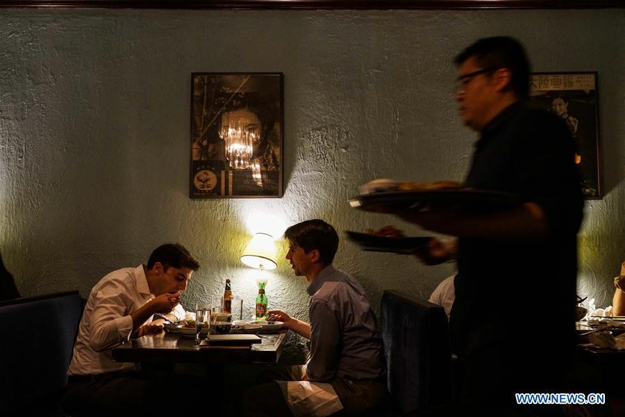 Customers have dinner at Cafe China in New York, the United States, on June 27, 2018. Walking in the bustling street of midtown Manhattan, you may not notice Cafe China if there weren\'t so many people waiting for seats outside the Chinese restaurant. Although the space is limited and decoration not so luxury, Cafe China has won Michelin one star for six consecutive years from 2012 to 2017. Wang Yiming and Zhang Xian, a couple from China, quit their well-paid financial jobs in New York and opened Cafe China with the ambition to provide authentic Sichuan cuisine along with a comfortable dining environment. They decided not to sell American-Chinese dishes like most Chinese restaurants did at that time. Meanwhile, the couple decorated the place with items such as vintage posters, antique cameras and lamps to create an old Shanghai style. At the beginning, their idea was strongly opposed by many friends and even their staff, as the American-Chinese food was the easiest way to make money at that time. However, it surprised them that many Americans swarmed to Cafe China with curiosity for decent Chinese dishes and the unique dining environment as soon as the restaurant just opened. The couple believed the success of Cafe China resulted from not only the appeal of authentic Chinese food but also the sophisticated Chinese culture behind it. \