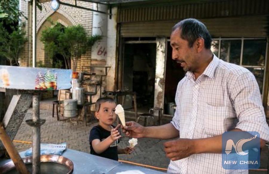 A little boy reaches eagerly for his second cone from an ice cream vendor in Kashgar on May 20. (Photo: Xinhua/Zhao Ge)

Nothing says summer quite like the taste of fresh, in-season produce. And a walk through the winding streets of Kashgar\'s old city is a feast for the senses: the air fragrant with ripe, juicy melons, and fresh tea, and the streets alive with the sound of stall owners hawking their wares.

There has been a settlement on the site of modern-day Kashgar for over 2,000 years. The trading hub was once an outpost on the ancient Silk Road, offering respite for weary travelers as they moved between China, the Middle East and Europe. Its commerce roots run deep and continue to this day. In 2010, the city was made into a Special Economic Zone, the only city in western China with such distinction.

The city is more than a tourist destination, however, and more and more people are moving to Kashgar, drawn to the dynamic, promising business environment.