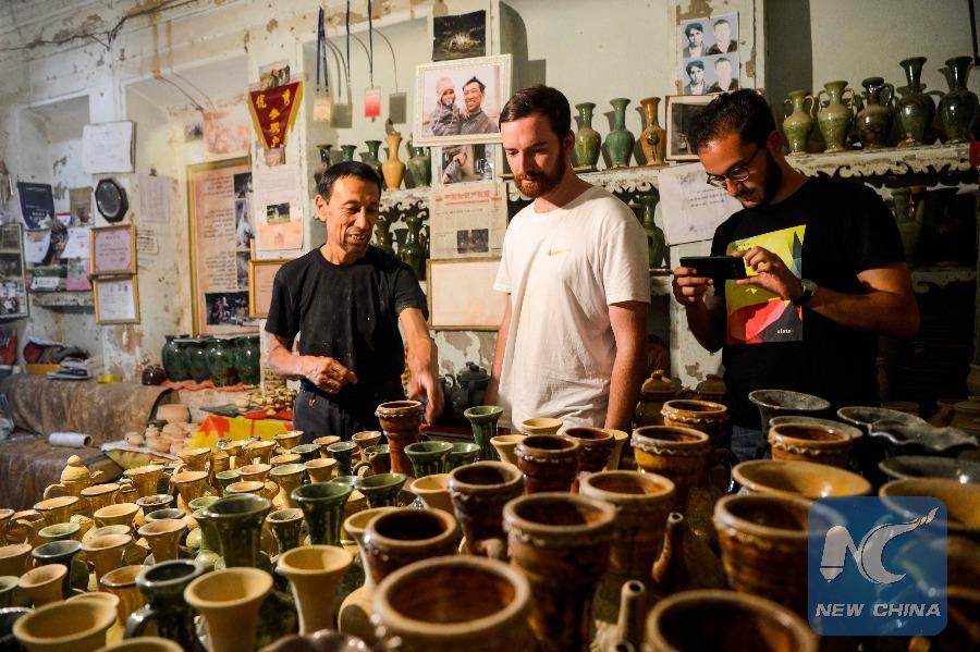 An Australian tourist selects pottery in Tursun Zunun\'s studio. (Photo: Xinhua/Zhao Ge)