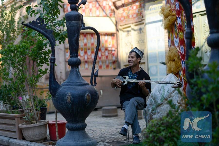 A Uygur man plays the rewap, a stringed instrument, in an alley at Kantuman Bazaar, Kashgar on July 11. (Photo: Xinhua/Zhao Ge)