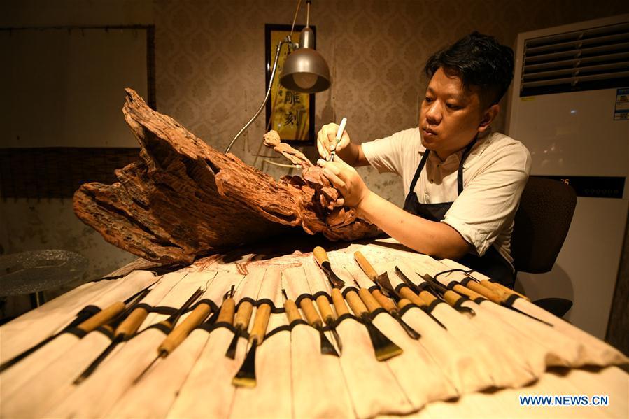 Craftsman Guo Dong makes wood carvings at a studio in Shijiazhuang, capital of north China\'s Hebei Province, July 20, 2018. The \