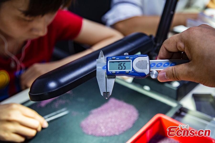 <?php echo strip_tags(addslashes(Staff members select gemstones in a jewelry store in Wuzhou City, South China’s Guangxi Zhuang Autonomous Region, July 24, 2018. They need to select at least 20,000 qualified pieces from more than 100,000 gemstones a day. Wuzhou is widely held to be the world capital for artificial gems and a trading center that now serves China and the rest of the world. Since the first factory was established there in 1982, Wuzhou now boasts an annual production value for the industry of approximately 3.2 billion yuan ($470 million). (Photo: China News Service/Chen Guanyan))) ?>