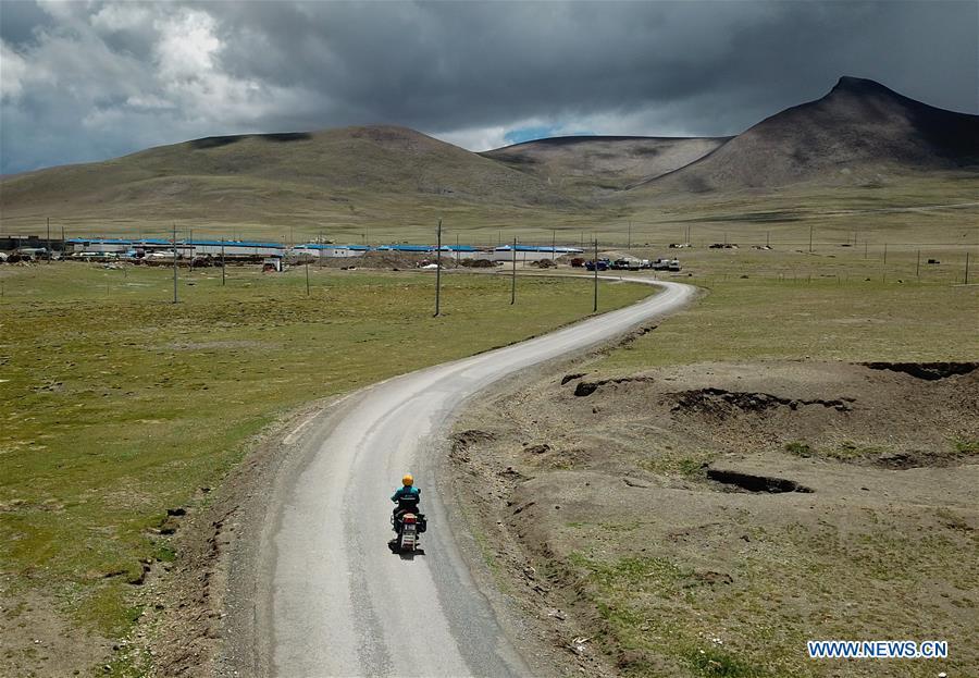 Motorbike courier Gesang Cering performs a mail delivery task in Pumaqangtang Township of Nagarze County in Shannan, southwest China\'s Tibet Autonomous Region, July 27, 2018. In Pumaqantang Township, the highest township in China, working as a postal service staff means delivering mails to addresses at altitudes of 5,000 meters and above. Gesang Cering, 29, is a motorbike courier with the local township branch of China Post. Twice a week, Gesang calls on the plateau villages under the township on a 160-km route, coping with extreme oxygen and temperature conditions. Despite its harsh geography, Tibet Autonomous Region has substantially improved the local postal service over the four decades since China\'s reform and opening up. By the end of 2017, the postal road network had managed to cover all towns and counties within the autonomous region. (Xinhua/Li He)