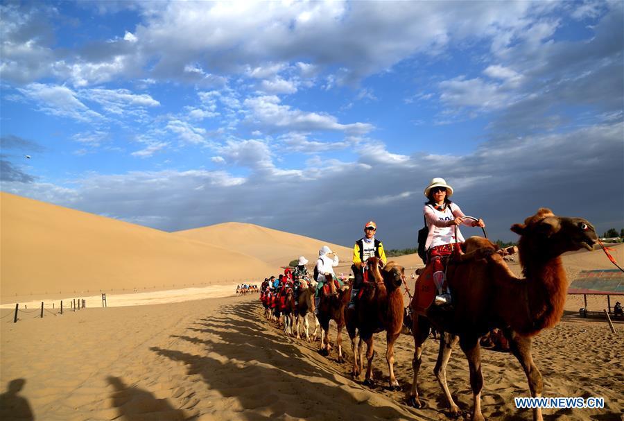 Tourists ride camels at the Mingsha Mountain and Crescent Spring scenic spot in Dunhuang, northwest China\'s Gansu Province, July 29, 2018. (Xinhua/Zhang Xiaoliang)