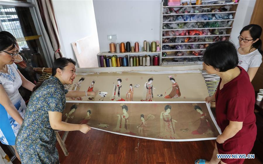 Wang Qin (2nd L) discusses Suzhou embroidery making skill with workers in east China\'s Jiangsu Province, July 25, 2018. An exhibition displaying Wang Qin\'s collections and creations of Suzhou embroidery version of classic Chinese painting works concluded in Suzhou on Sunday. (Xinhua/Yang Lei)