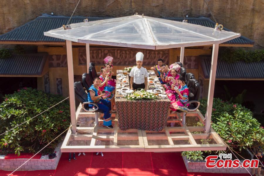 Participants face the challenge of eating rice noodles in a transparent room, hoisted 50 meters off the ground, near a giant statue at a scenic spot in Guilin City, South China’s Guangxi Zhuang Autonomous Region, July 29, 2018. Scared of the height, the participants gave up on the dare when the room was just ten meters off the ground. (Photo: China News Service/Chen Chen)