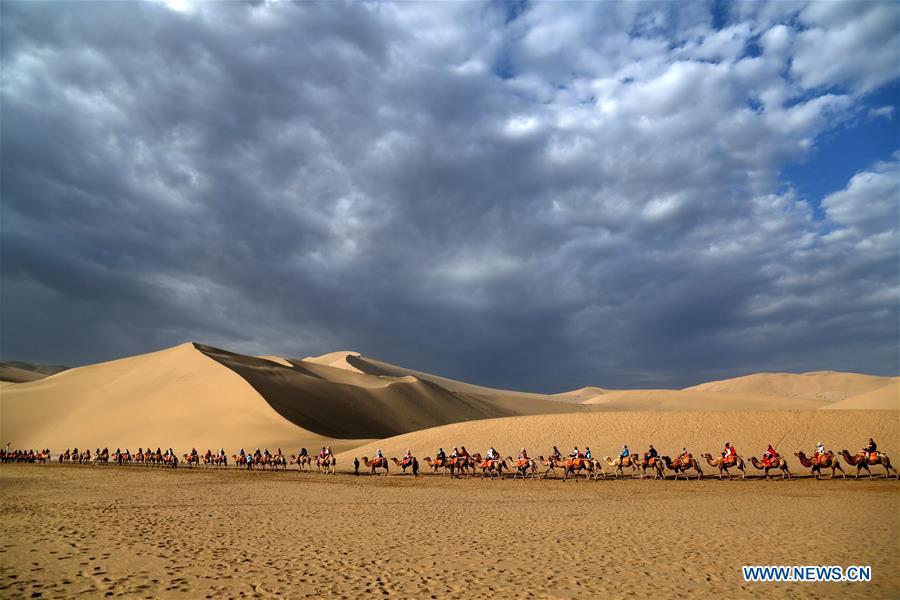 Tourists ride camels at the Mingsha Mountain and Crescent Spring scenic spot in Dunhuang, northwest China\'s Gansu Province, July 29, 2018. (Xinhua/Zhang Xiaoliang)