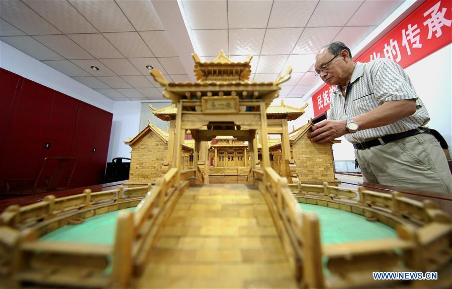 Zhang Xiaocheng checks a model of ancient building made of discarded wooden sticks in Chengguan Town of Wu\'an City, north China\'s Hebei Province, July 31, 2018. 70-year-old Zhang has made over 60 handicrafts using discarded wooden sticks. (Xinhua/Wang Xiao)