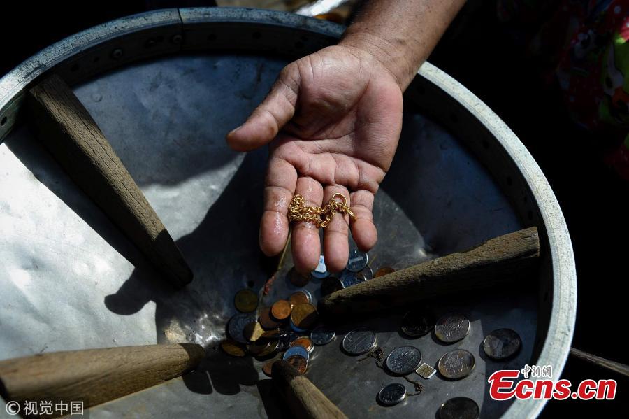 This photo taken on June 12, 2019 shows diver Bhoomin Samang holding jewellery and rare coins he found during previous diving trips to the bottom of Bangkok\'s Chao Phraya River. There is a small community in Thailand known as \'Indiana Jones\' divers, who brave the inky-black underworld of the trash-filled waterway in search of coins, china, jewelry and scrap metal. (Photo/VCG)