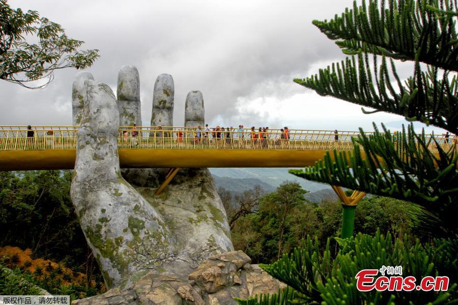 <?php echo strip_tags(addslashes(In this photograph taken on July 31, 2018, visitors walk along the 150-meter long Cau Vang 'Golden Bridge' in the Ba Na Hills near Danang. Nestled in the forested hills of central Vietnam two giant concrete hands emerge from the trees, holding up a glimmering golden bridge crowded with gleeful visitors taking selfies at the country's latest eccentric tourist draw. Suspended 1400 meters above sea level, the bridge combines eight sections and stretches 150 meters long. (Photo/VCG))) ?>