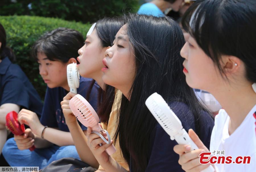 A middle school student holds a portable fan amid the sweltering heat during a rally demanding full compensation and apology for wartime sex slaves from Japanese government in front of the Japanese embassy in Seoul, South Korea, Aug. 1, 2018. South Korean Meteorological Administration issued a heat wave warning for Seoul and other cities. (Photo/Agencies)