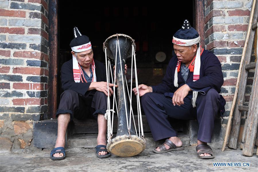 Villagers Pan Zhensong (L) and Pan Zhiming talk about making Huangni drums in Jinxiu Yao Autonomous County, south China\'s Guangxi Zhuang Autonomous Region, Aug. 1, 2018. The local Huangni drum dance was listed as one of the national intangible cultural heritage in 2011. (Xinhua/Lu Boan)