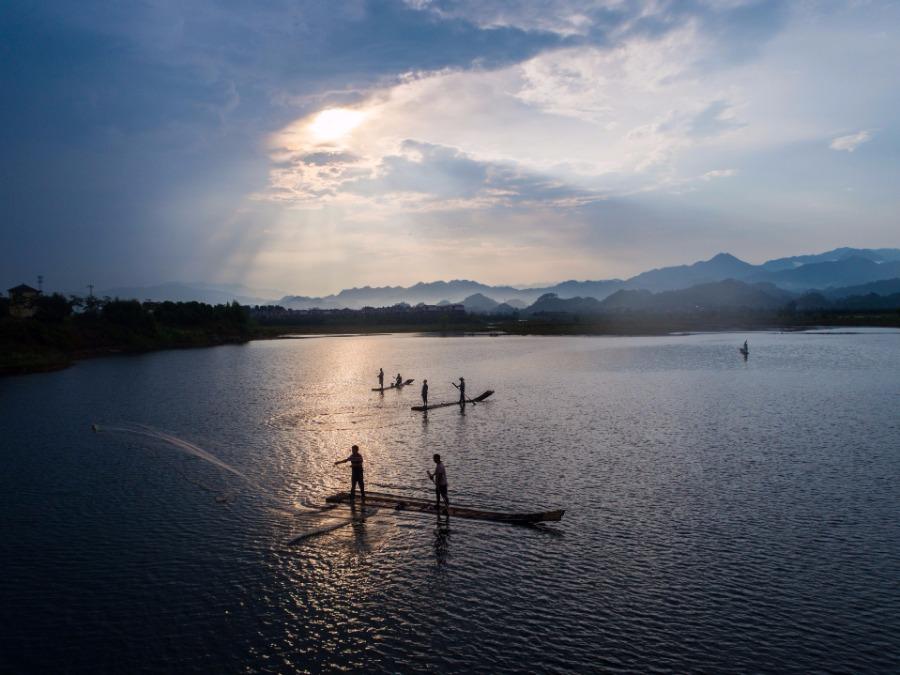 Fishermen cast nets on a bamboo raft on Qiandao Lake, Hangzhou city, Zhejiang Province, Aug. 2, 2018. After a three-month break, fishermen resume a new round of catches in the area, where rural tourism and recreational fishing are highlights of the local industry. (Photo/Xinhua)
