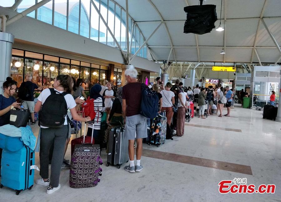 Tourists wait at Indonesia\'s Lombok international airport to evacuate from the resort land after a 7.0-magnitude quake hit the island on Sunday. Death toll from the quake rose to 98, with hundreds of others injured. The quake caused minor damage to Lombok international airport in Lombok and Ngurah Rai International Airport in Bali. (Photo: China News Service/Lin Yongchuan)