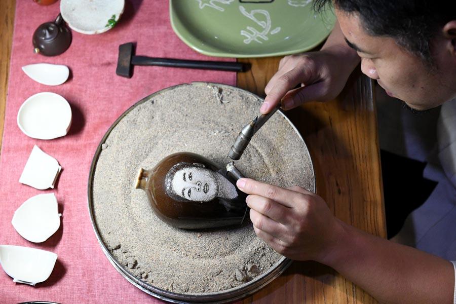 Li Junhang creates a portrait on a porcelain piece on Aug., 6, 2018. (Photo/Xinhua)