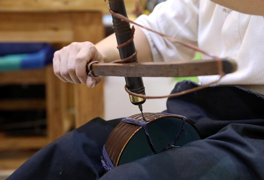 Li Junhang drills a hole for a broken porcelain ware, Aug. 6, 2018.  (Photo/Xinhua)