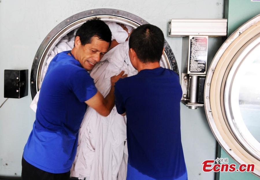 Workers clean bedding for sleeper carriages on trains in Jiujiang City, East China’s Jiangxi Province, Aug. 8, 2018. During the summer travel peak, laundry service workers have to clean up to 20,000 sets of linen a day, double their normal workload, despite the high temperatures at 50 degrees centigrade. (Photo: China News Service/Hu Guolin)