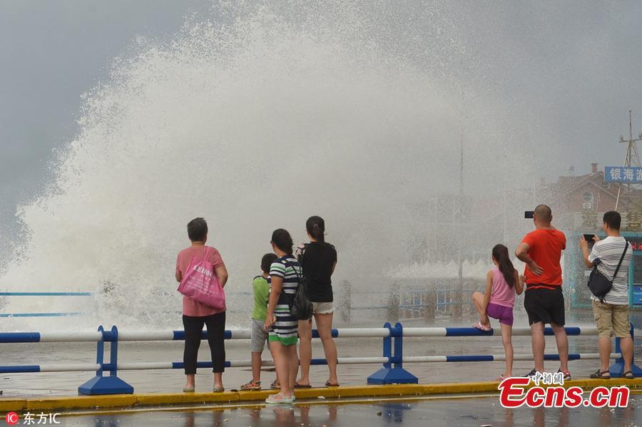 Visitors watch as huge waves, caused by Typhoon Yagi, pound the beach in Qingdao City, East China’s Shandong Province, Aug. 14, 2018. (Photo/IC)