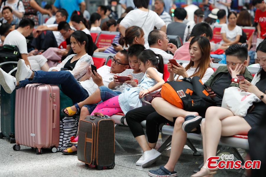 Passengers wait to change or refund tickets at a railway station in Shanghai, Aug. 13, 2018, after several trains were canceled due to Typhoon Yagi. Emergency rescuers are bracing for this year\'s 14th typhoon in the metropolis. (Photo: China News Service/Yin Liqin)
