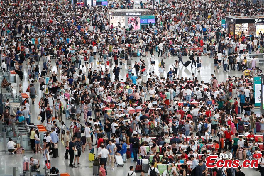 Passengers wait to change or refund tickets at a railway station in Shanghai, Aug. 13, 2018, after several trains were canceled due to Typhoon Yagi. Emergency rescuers are bracing for this year\'s 14th typhoon in the metropolis. (Photo: China News Service/Yin Liqin)