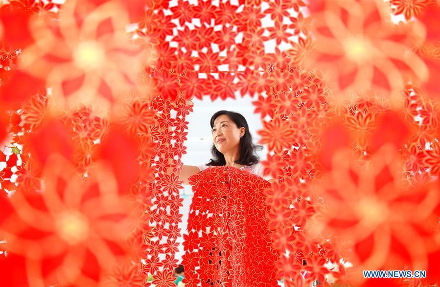 A woman hangs embroidery works for drying at a factory in Yiyuan County of Zibo City, east China\'s Shandong Province, Aug. 13, 2018. In recent years, Yiyuan government has made efforts on the development of knitting and embroidery industry. Through establishing cooperatives and industry associations, the government helps to open up domestic and international market for products and raise income for the locals. (Xinhua/Zhao Dongshan)