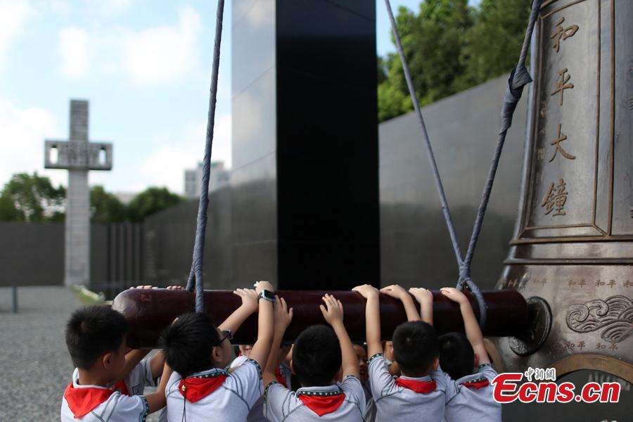 Students strike the Peace Bell at the Memorial Hall of the Victims in Nanjing Massacre by Japanese Invaders in Nanjing, Jiangsu Province, Aug. 15, 2018. Peace lovers from home and abroad, volunteers, soldiers and students attended the ceremony to pray for peace in the world. (Photo: China News Service/Yang Bo)
