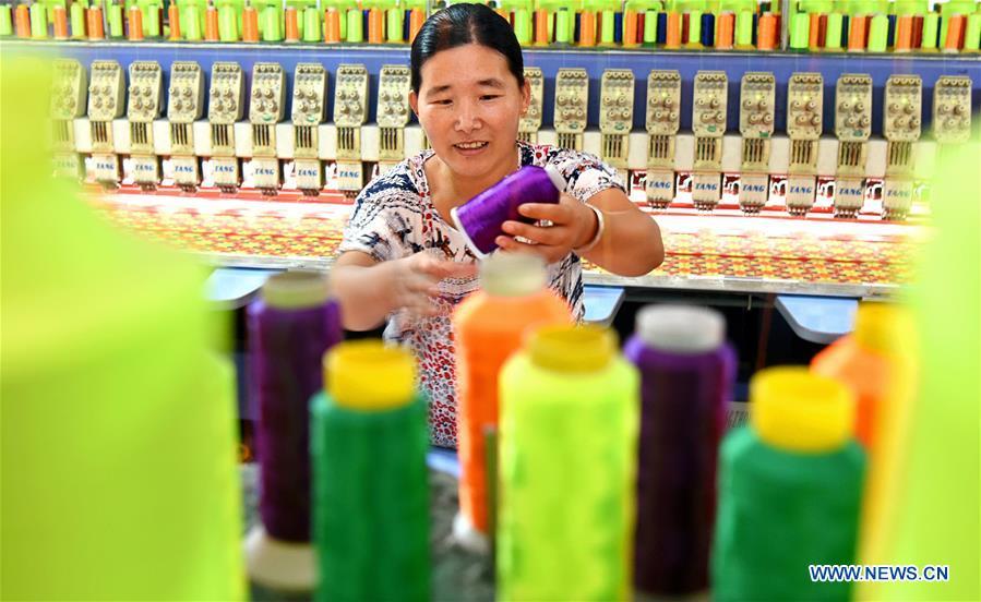 A woman works in a knitting workshop in Gezhuang Village of Shiqiao Town in Yiyuan County, east China\'s Shandong Province, Aug. 14, 2018. In recent years, Yiyuan government has made efforts on the development of knitting and embroidery industry. Through establishing cooperatives and industry associations, the government helps to open up domestic and international market for products and raise income for the locals. (Xinhua/Zhao Dongshan)