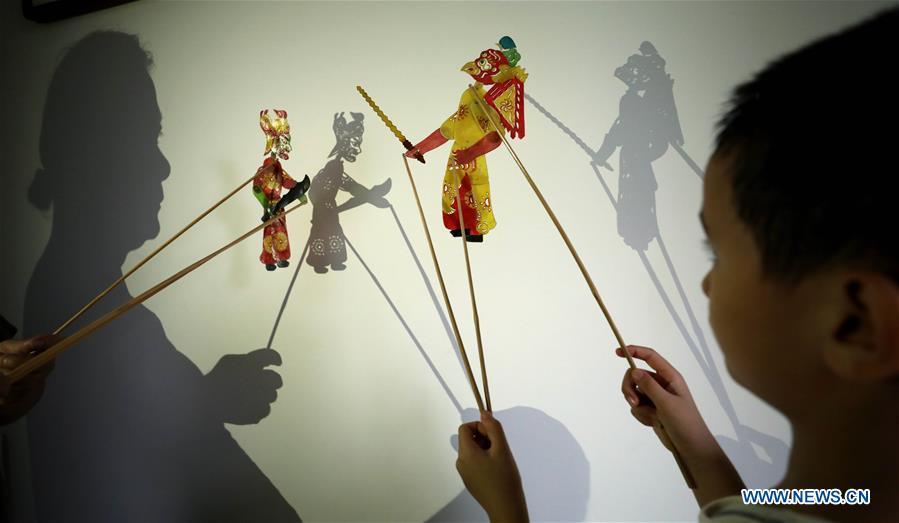 Li Wei and his grandson perform a shadow puppet show in Jinan, east China\'s Shandong Province, Aug. 14, 2018. Li, 63, is the son of Jinan shadow puppet show master Li Xingtang. He learned shadow puppet performance from his father in childhood. After his father passed away 11 years ago, Li Wei took over the task of developing and innovating the art of Jinan puppet show. Since last summer, Li has kept on presenting traditional shadow puppet plays at the Baihuazhou scenic area in Jinan every weekend for free. (Xinhua/Zhao Xiaoming)