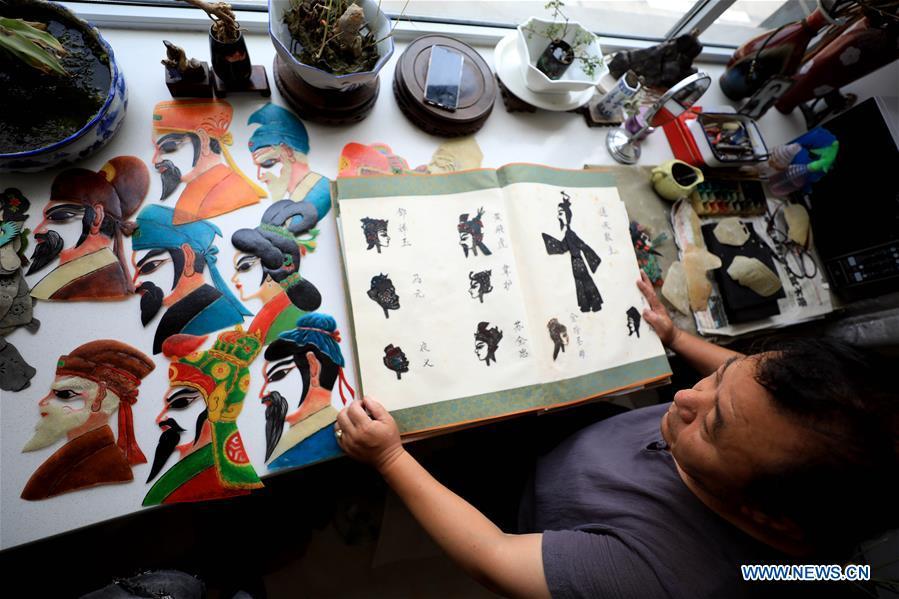 Li Wei shows shadow puppets made by himself in Jinan, east China\'s Shandong Province, July 5, 2018. Li, 63, is the son of Jinan shadow puppet show master Li Xingtang. He learned shadow puppet performance from his father in childhood. After his father passed away 11 years ago, Li Wei took over the task of developing and innovating the art of Jinan puppet show. Since last summer, Li has kept on presenting traditional shadow puppet plays at the Baihuazhou scenic area in Jinan every weekend for free. (Xinhua/Zhao Xiaoming)