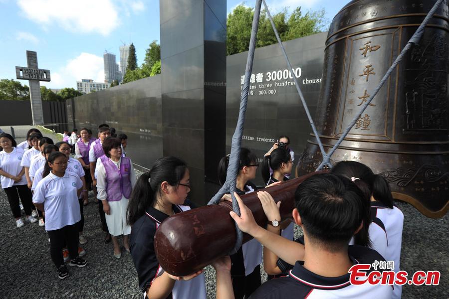 Students strike the Peace Bell at the Memorial Hall of the Victims in Nanjing Massacre by Japanese Invaders in Nanjing, Jiangsu Province, Aug. 15, 2018. Peace lovers from home and abroad, volunteers, soldiers and students attended the ceremony to pray for peace in the world. (Photo: China News Service/Yang Bo)