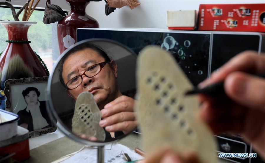 Li Wei carves shadow puppet accessories in Jinan, east China\'s Shandong Province, July 11, 2018. Li, 63, is the son of Jinan shadow puppet show master Li Xingtang. He learned shadow puppet performance from his father in childhood. After his father passed away 11 years ago, Li Wei took over the task of developing and innovating the art of Jinan puppet show. Since last summer, Li has kept on presenting traditional shadow puppet plays at the Baihuazhou scenic area in Jinan every weekend for free. (Xinhua/Zhao Xiaoming)
