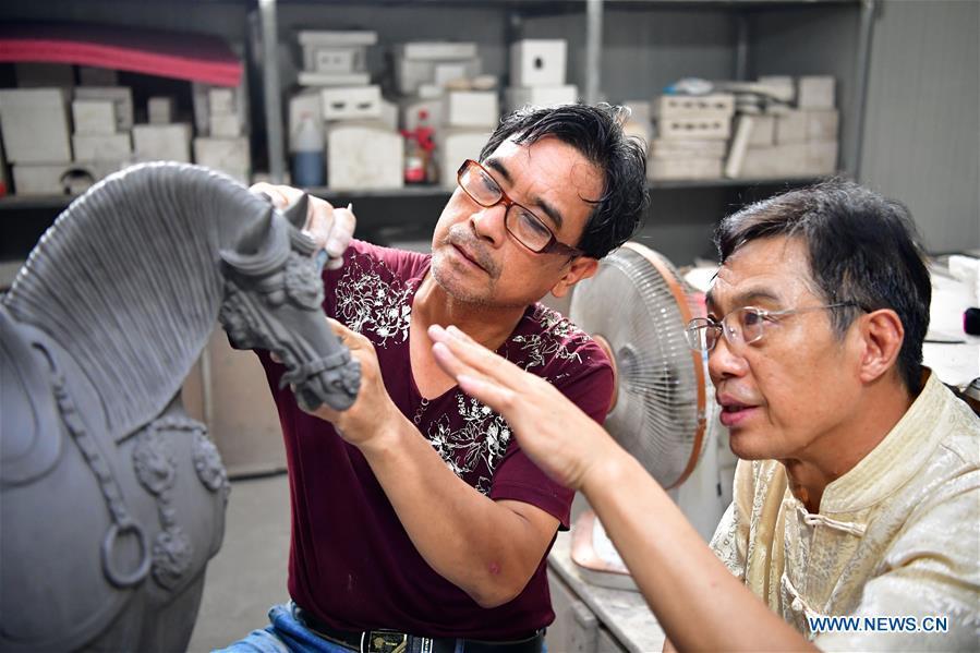Tri-colored glazed pottery technique inheritor Gao Shuiwang (R) teaches his apprentice in Nanshishan Village, Mengjin County, Luoyang City, central China\'s Henan Province, Aug. 15, 2018. Gao is a leading figure in the revival of tri-colored glazed pottery, or Sancai, a Chinese porcelain characterized by a glaze with three intermingled colours. The producing technique of Sancai, which flourished in the Tang Dynasty (618-907 AD), was very complex and listed as one of China\'s National Intangible Heritages in 2008. Nanshishan Village in Henan is regarded as an important village of Sancai culture, with more than 70 enterprises now engaging in the industry. (Xinhua/Feng Dapeng)