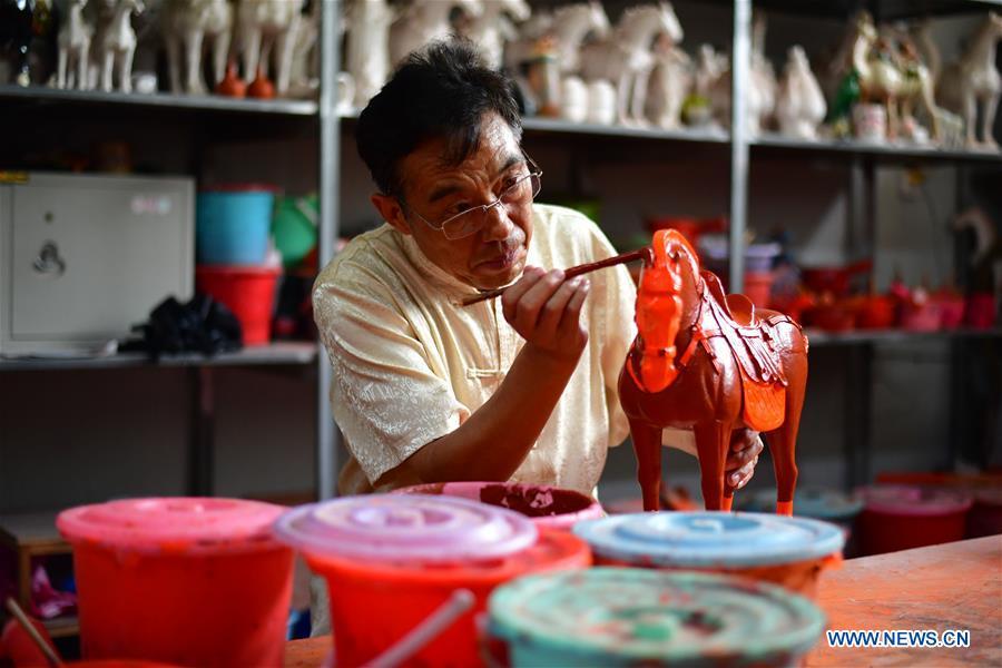 <?php echo strip_tags(addslashes(Tri-colored glazed pottery technique inheritor Gao Shuiwang makes a horse pottery in Nanshishan Village, Mengjin County, Luoyang City, central China's Henan Province, Aug. 15, 2018. Gao is a leading figure in the revival of tri-colored glazed pottery, or Sancai, a Chinese porcelain characterized by a glaze with three intermingled colours. The producing technique of Sancai, which flourished in the Tang Dynasty (618-907 AD), was very complex and listed as one of China's National Intangible Heritages in 2008. Nanshishan Village in Henan is regarded as an important village of Sancai culture, with more than 70 enterprises now engaging in the industry. (Xinhua/Feng Dapeng))) ?>