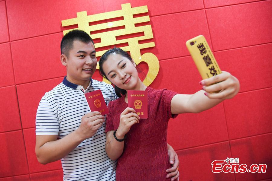 A couple poses for a photo as they complete their marriage registration at the civil affairs department in Taiyuan City, Shanxi Province, Aug. 17, 2018 on the Qixi Festival, known as China’s Valentine\'s Day. Falling on the seventh day of the seventh lunar month on the Chinese calendar, the festival celebrates the annual meeting of a cowherd and weaver girl in Chinese mythology. Some reportedly got up at 5 am to register on a day considered auspicious. (Photo: China News Service/Wu Junjie)