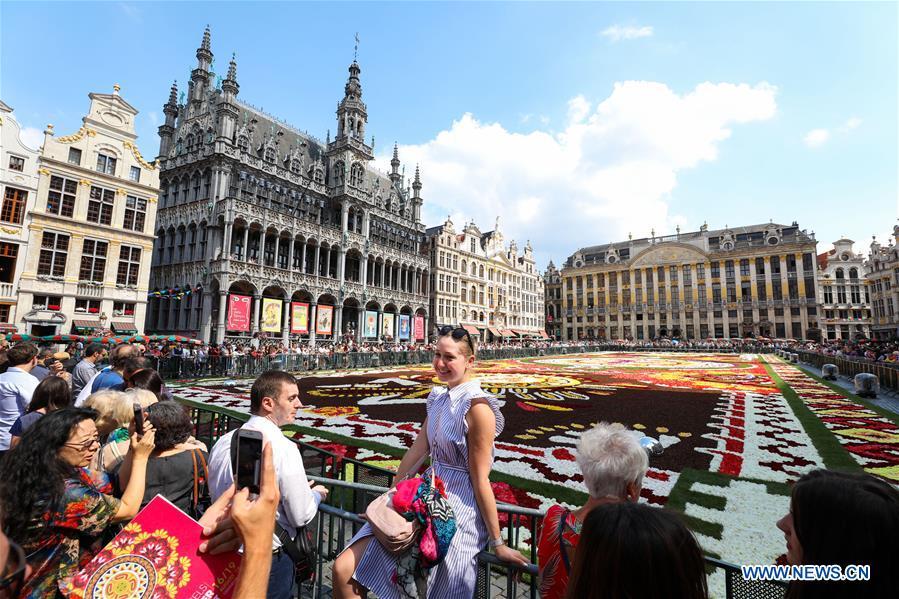 A girl poses for photos beside the Flower Carpet at the Grand Place in Brussels, Belgium, Aug. 17, 2018. The Flower Carpet 2018 is held at the Grand Place in Brussels from Aug. 16 to Aug. 19. This year\'s carpet is dedicated to Guanajuato, a Mexican region with rich floral culture and tradition. (Xinhua/Zheng Huansong)