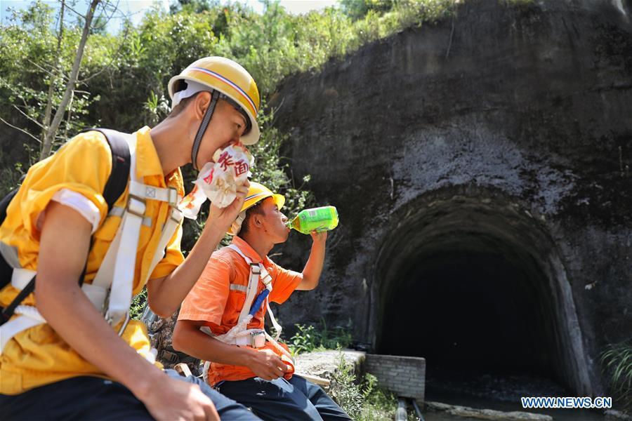 Staff members eat lunch in front of the Yindongpo Tunnel of Guizhou-Guangxi Railway in Duyun City, southwest China\'s Guizhou Province, Aug. 20, 2018. Railway maintenance workers here patrolled the 8.5-kilometer tunnel and took necessary measures to ensure the safety of railway transportation during the flood season. (Xinhua/Liu Xu)