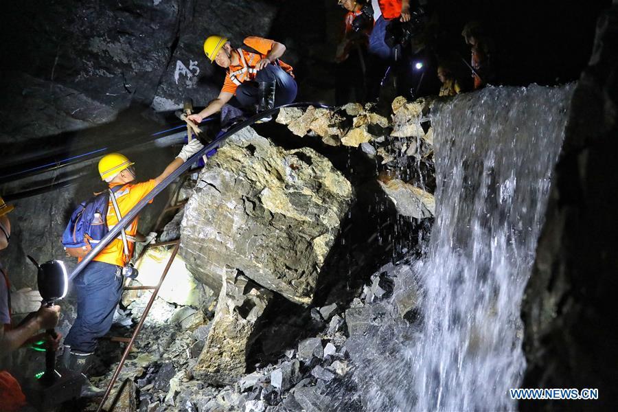 Staff members pass a stream of flowing water while patrolling the Yindongpo Tunnel of Guizhou-Guangxi Railway in Duyun City, southwest China\'s Guizhou Province, Aug. 20, 2018. Railway maintenance workers here patrolled the 8.5-kilometer tu