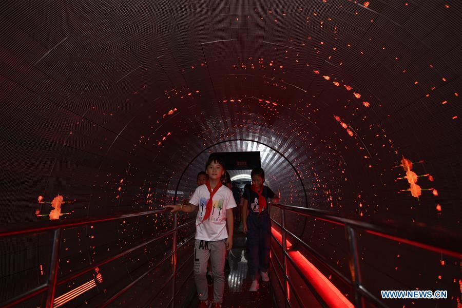 Children walk through an illuminated corridor during a visit to the Anhui provincial science museum in Hefei, east China\'s Anhui Province, Aug. 23, 2018. A local community organized a museum tour for children on Thursday. (Xinhua/Ge Yinian)