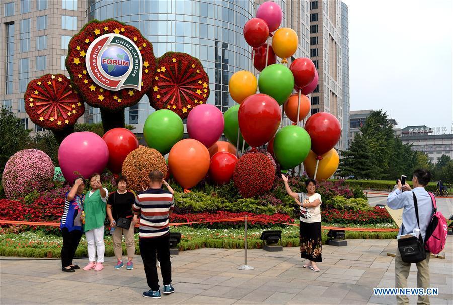 Tourists pose for photo in front of a parterre to greet the 2018 Beijing summit of the Forum on China-Africa Cooperation (FOCAC) in Beijing, capital of China, Aug. 28, 2018. The summit is scheduled for Sept. 3-4 in Beijing. (Xinhua/Luo Xiaoguang)