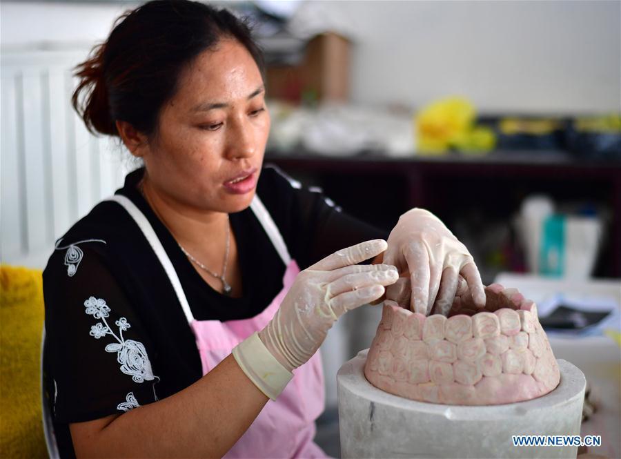 A craftswoman works on a greenware at Dangyangyu Village of Xiuwu County in Jiaozuo, central China\'s Henan Province, Aug, 27, 2018. The Dangyangyu kiln Jiao Tai pottery firing is a handicraft that was listed as a national intangible cultural heritage in 2014. The Jiao Tai pottery is made by blending clays of differing colours together, creating distinctive veined or mottled patterns. The handicraft is therefore recognized as \